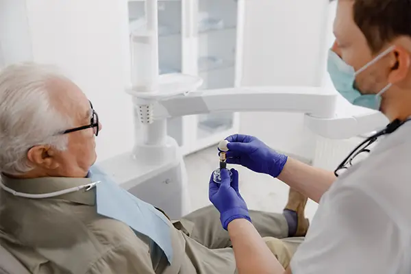 A dentist explains the dental implant process to an older patient at Periodontal Surgical Arts in Austin, TX